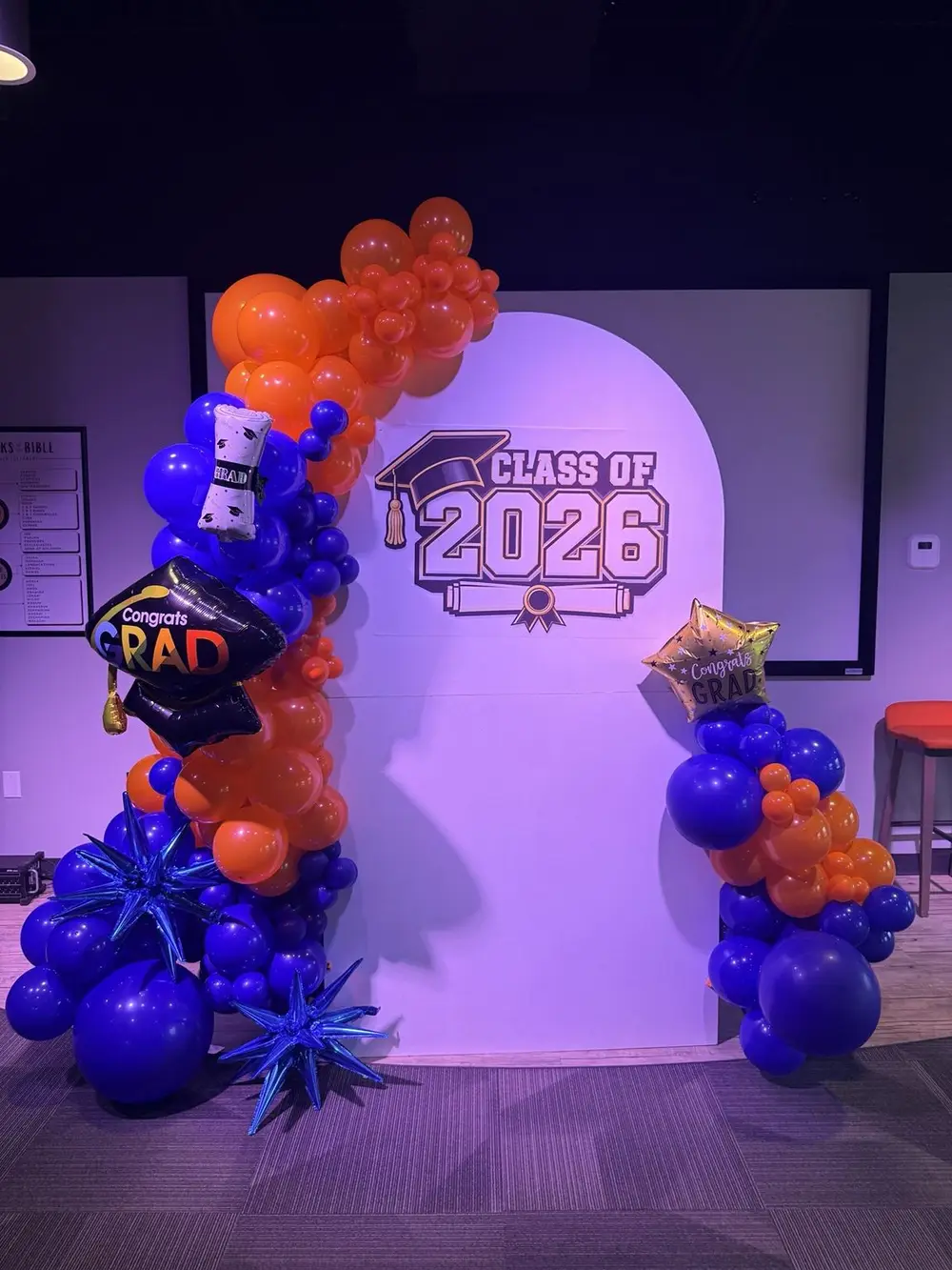 Graduation backdrop with orange and royal blue balloons