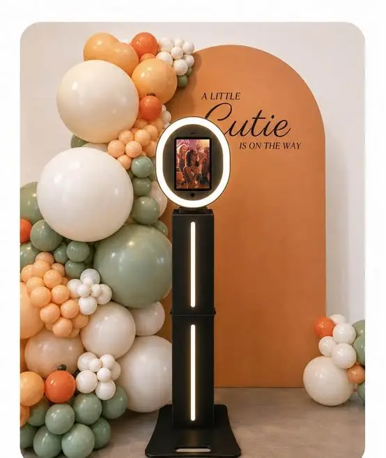 Photo booth with a terracotta arch, balloon garland, and custom vinyl lettering